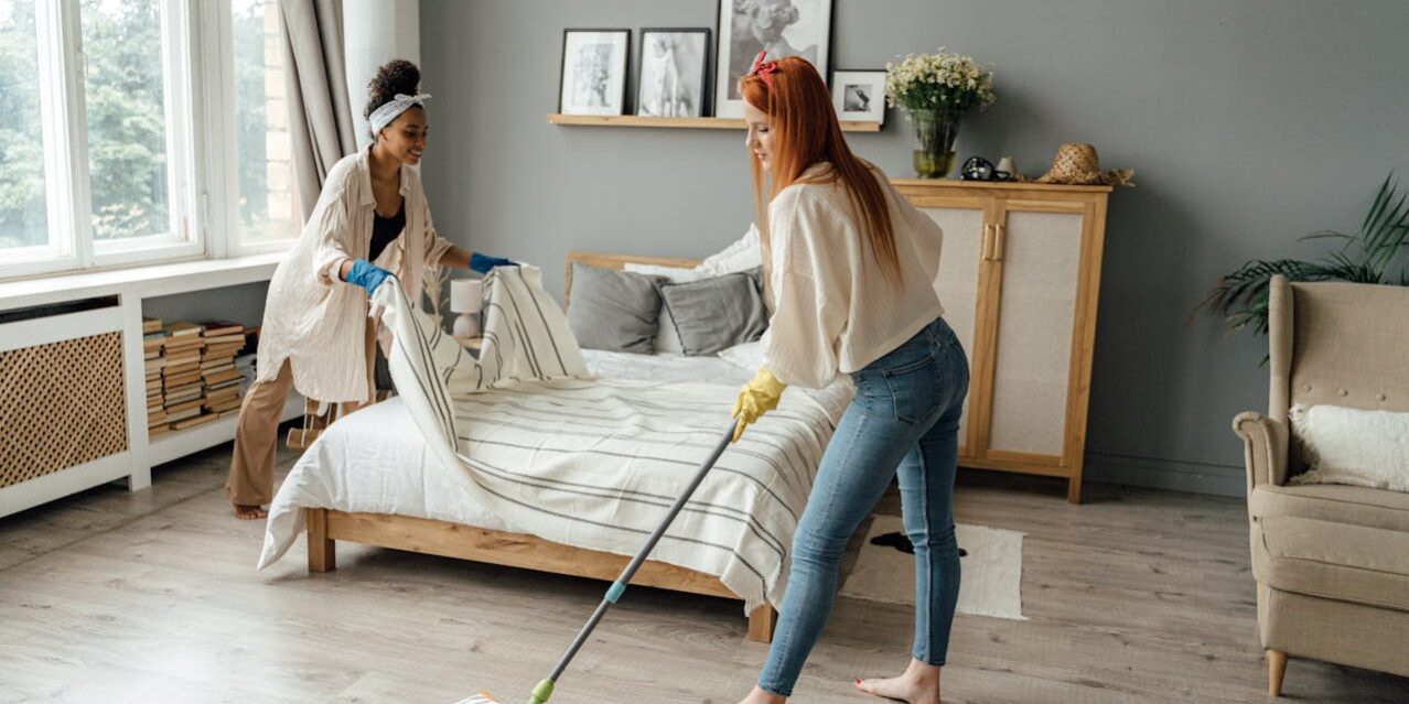 Twee vrouwen die hun slaapkamer aan het schoonmaken zijn
