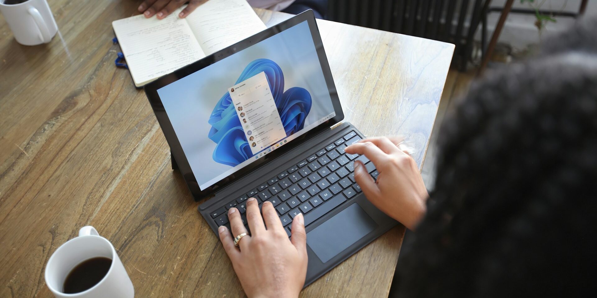 Persoon werkt met slimme software op een laptop tijdens een overleg, met focus op communicatie en planning.