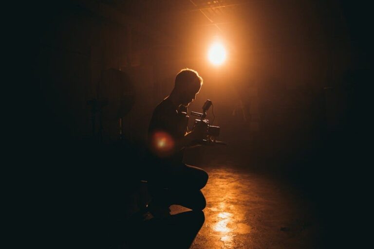 Filmmaker werkt met camera in donkere studio, belicht door warme spot, passend bij high-tech visuals in merkbeleving.