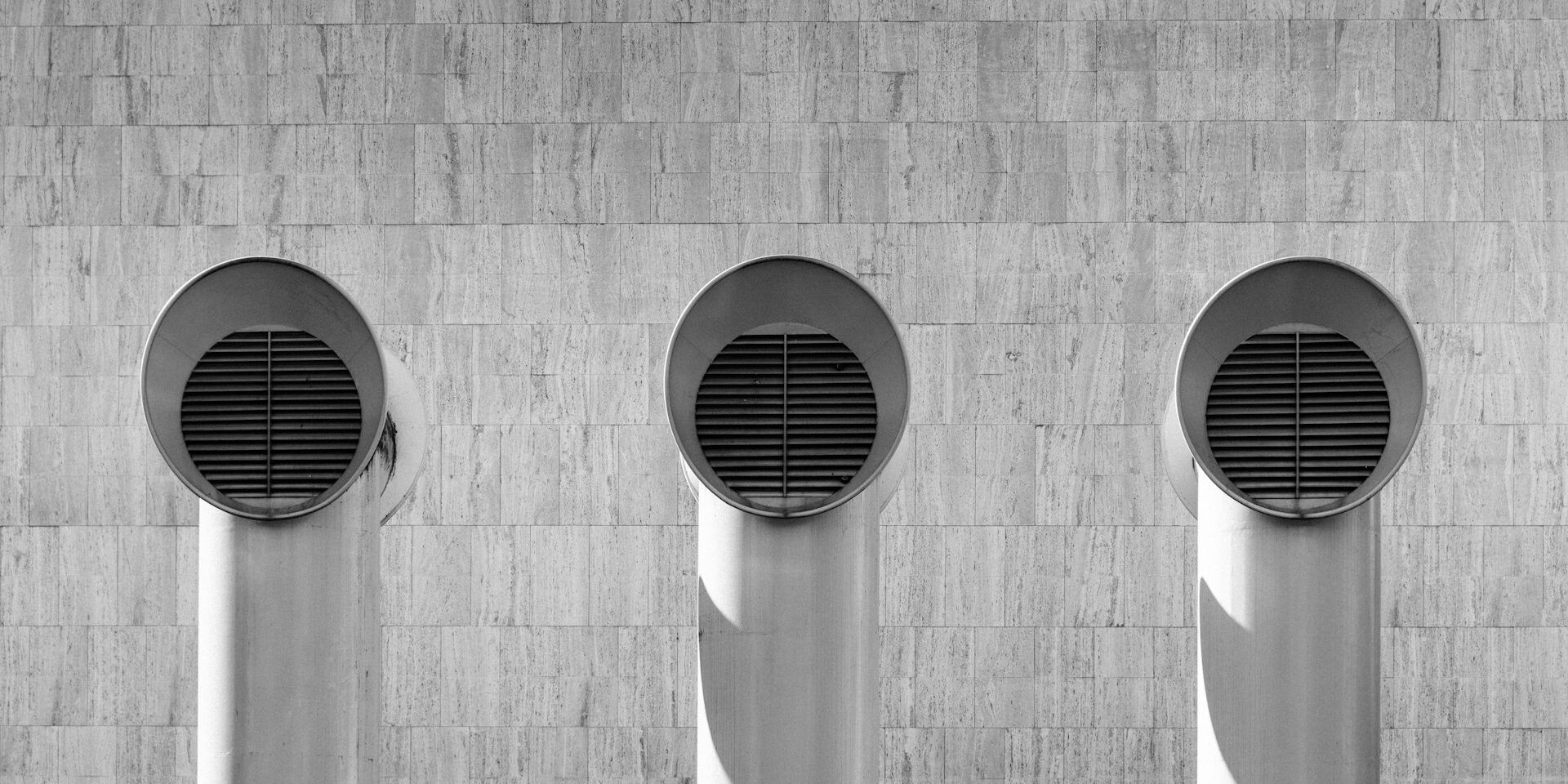 Drie ronde ventilatie-uitlaten op een betonnen gevel, geschikt voor ventilatie in bestaande woningen.