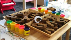 Educatief speelgoed met houten letters en Play-Doh op tafel, passend bij thuiswerken en gezin combineren