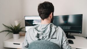 Man werkt thuis aan een bureau met dubbele monitoren, in balans met gezin combineren