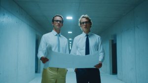 Twee bouwprofessionals bekijken een uitgerold bouwplan in een betonnen gang tijdens de voorbereiding van een project